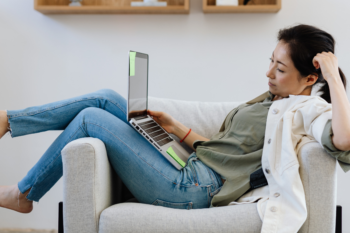 Woman sat on a armchair looking at a laptop