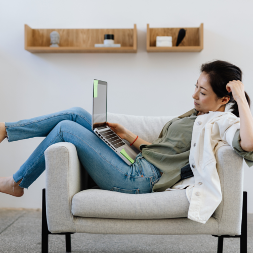 Woman sat on a armchair looking at a laptop