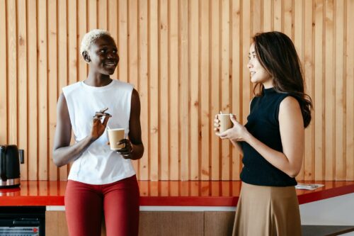 2 smartly dressed women sharing their thoughts on EMI schemes over a takeaway coffee