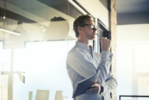 Man with glasses, standing in his office thinking about financial ratios