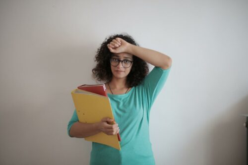 Woman looking stressed holding folders of bookkeeping and accounting paperwork