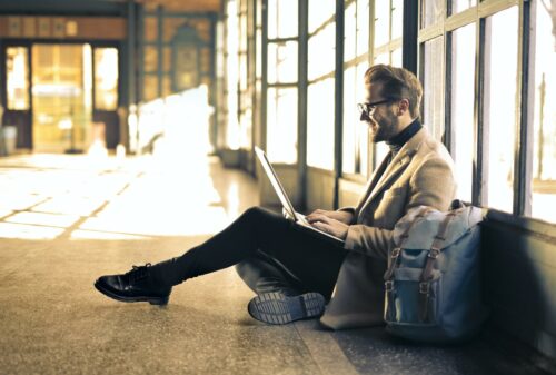 man smiling at laptop wearing blazer after nailing contract management automation