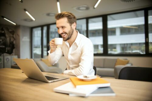 Man enjoying a coffee at his desk after contract management automation makes his life simple