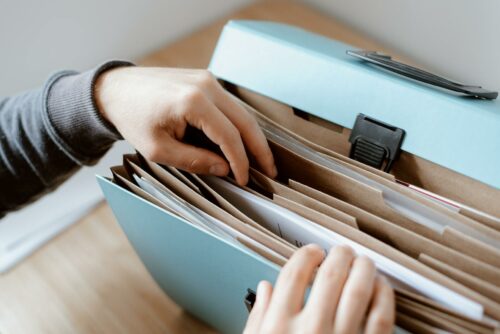Hands searching through files to find information about national insurance for employers
