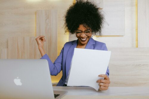 Woman at laptop smiling at papers for business accounting services