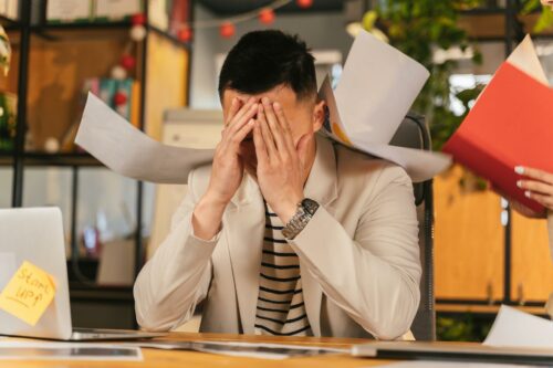 Man looking stressed with paperwork flying around for self assessment 2022