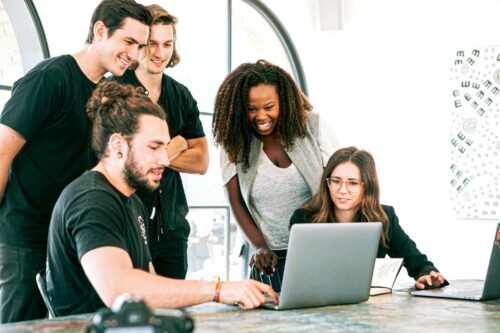 Co-workers gathered around a laptop smiling about new website