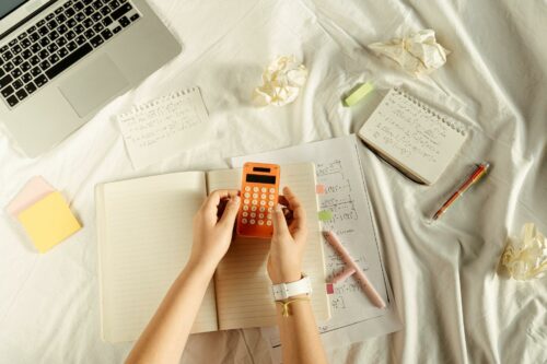 Person calculating unit economics on an orange calculator and notepad