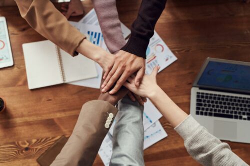 Hands all together in a huddle in an angel investment network
