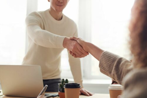 man and woman shaking hands after a deal that will affect financial ratios
