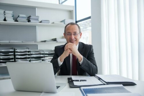 Man smiling at camera over laptop, after discovering these great R&D tax credit examples