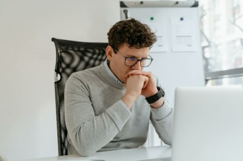 Man in jumper and glasses deep in thought, trying to decide if a CFO is worth the cost