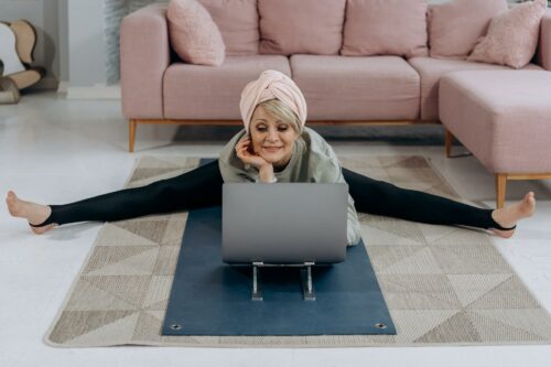 Woman stretching on laptop, taking part in a class from a fitness startup