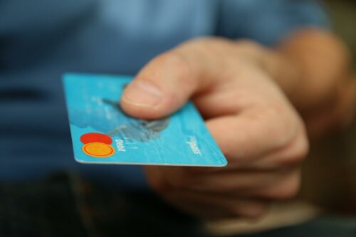 Hand holding out a payment card - signifying a customer paying early or on time, to help with cash flow management