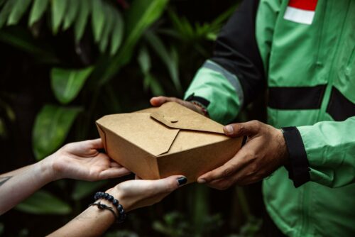 Delivery man handing customer parcel, using a logistics startup