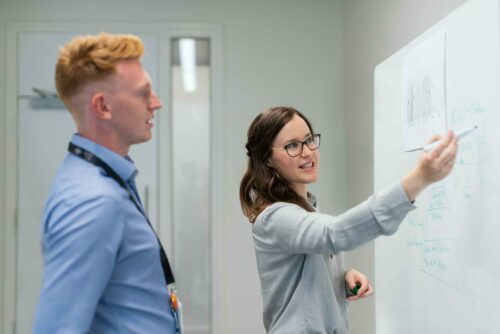 Woman explaining angel investment networks on a whiteboard to a colleague