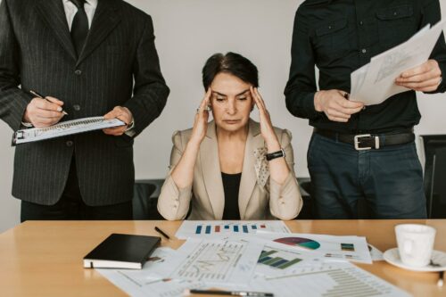 Woman looking overwhelmed by paperwork, realising she needs payroll software